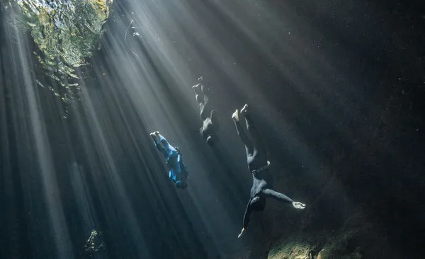 3 freedivers diving in one of the cenotes in Mexico