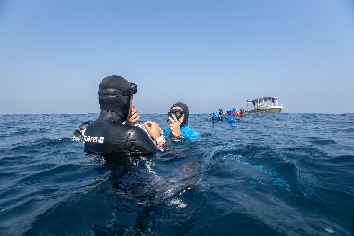 A freediving instructor teaching a student in open water