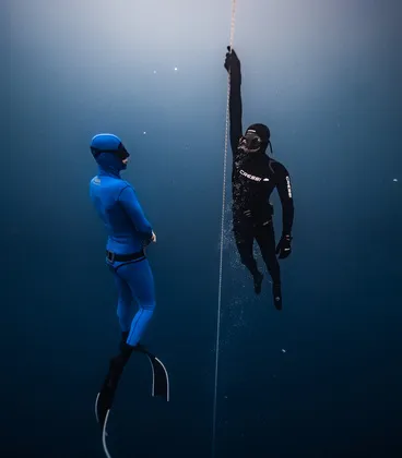 A freediving instructor safely ascending with a freediver