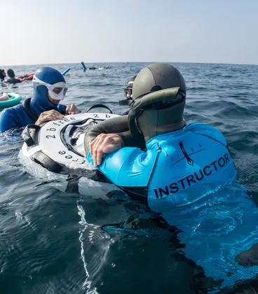 A freediving instructor teaching a student on the buoy