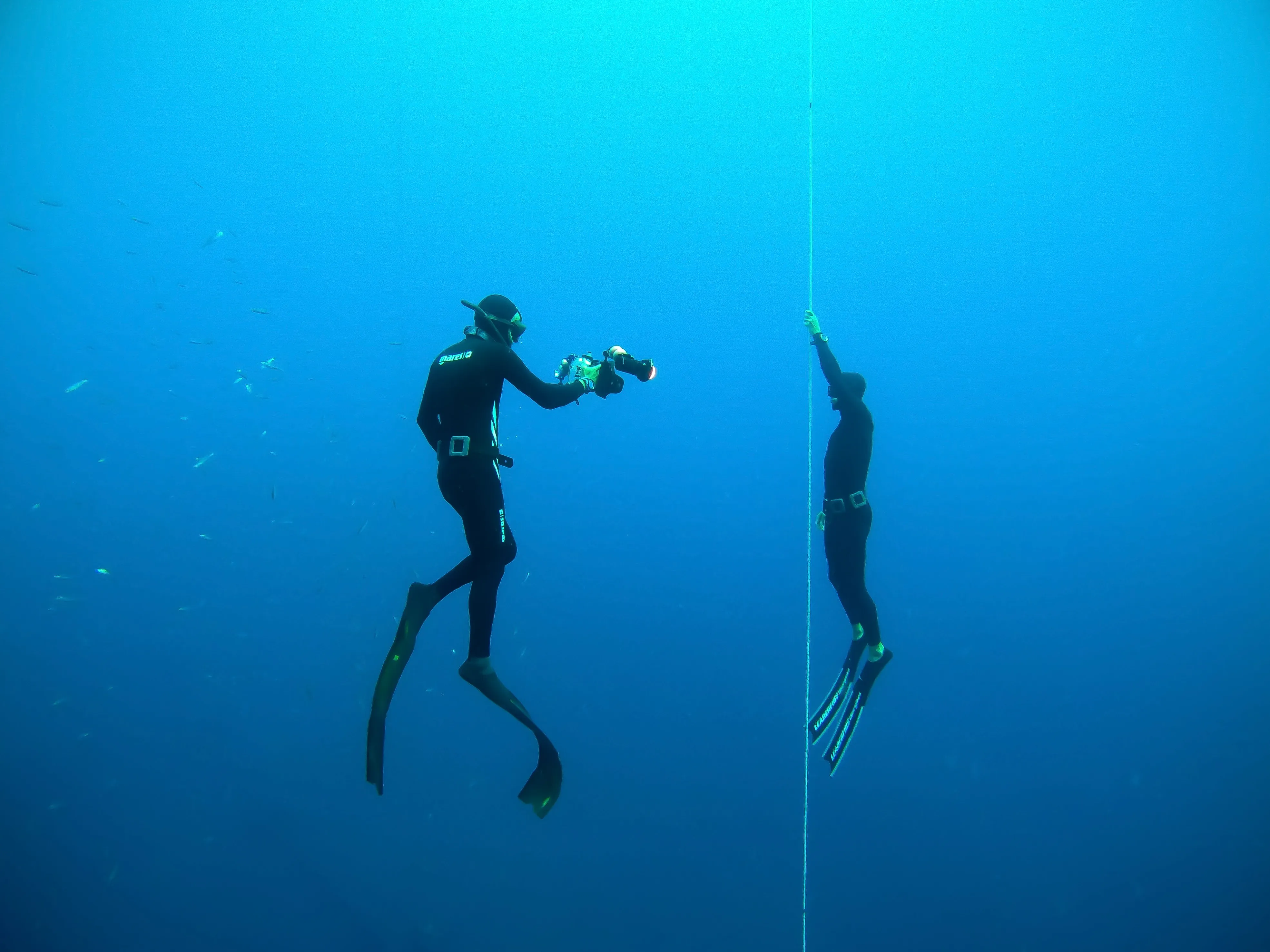 A freediving instructor is filming and ascending with a student in a lake in Zurich, Switzerland.